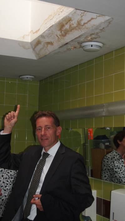 Besuch der Gustav-Werner-Schule am 15.05.2015 - Dr. Thomas Kienle weist auf Schäden in den Umkleiden hin.